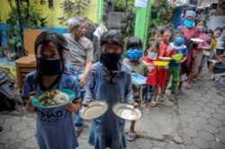 Locals wearing protective masks carry plates while queueing for food distributed for free amid the spread of coronavirus disease (COVID-19) in Bandung, West Java province, Indonesia, April 10, 2920..