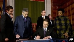 Gubernur New York, Andrew Cuomo, menandatangani "NY Safe Act" di Albany, New York, 15 Januari 2013. (AP Photo/Mike Groll). New York menjadi negara bagian pertama di Amerika yang memberlakukan aturan untuk memperketat penggunaan senjata api.