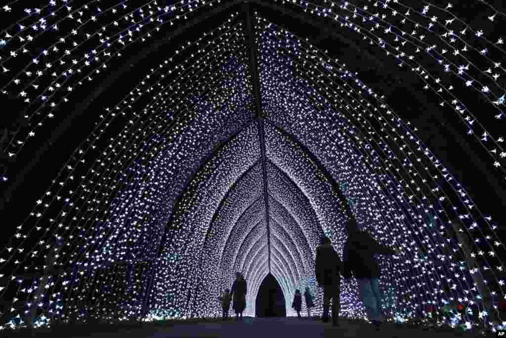 Para pengunjung berjalan melalui &#39;Katedral&#39; di jalur lampu Natal saat perayaan tahun ke-12 pameran instalasi baru yang terletak di lanskap Situs Warisan Dunia UNESCO di Kew Gardens di London. (AP)&nbsp;