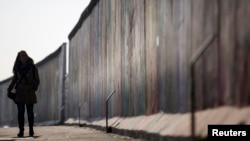 FILE - A woman walks along the former Berlin Wall, now called East Side Gallery, in Berlin March 4, 2013.