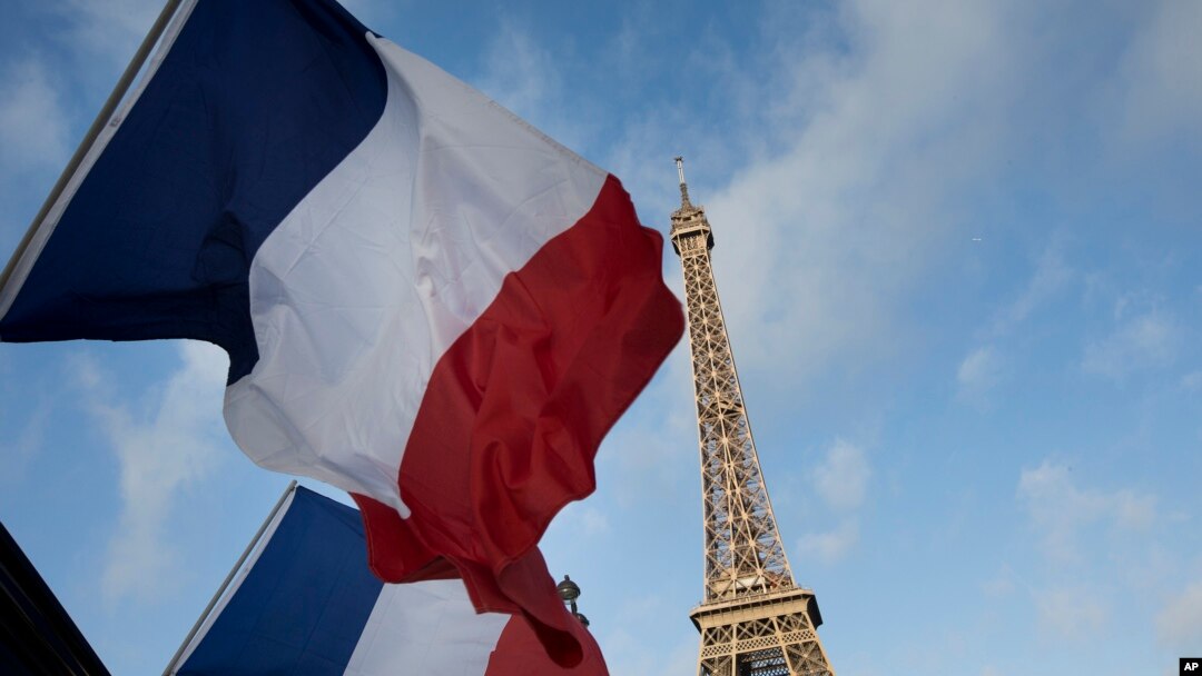 French flags fly as the closed Eiffel Tower is seen in the background on the first of three days of national mourning in Paris, Nov. 15, 2015. 
