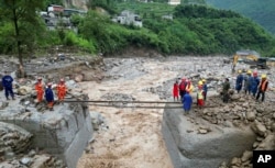 Petugas penyelamat membuat penyeberangan setelah ambruk karena hujan pada 20 Juli 2024. (Xinhua via AP)