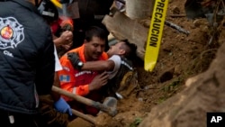 A fireman is rescued after he was trapped while working at the site of a landslide in Cambray, a neighborhood in the suburb of Santa Catarina Pinula, about 10 miles east of Guatemala City, Oct. 3, 2015. 