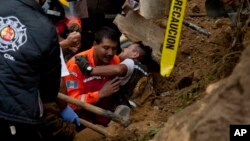 A fireman is rescued after he was trapped while working at the site of a landslide in Cambray, a neighborhood in the suburb of Santa Catarina Pinula, about 15 kilometers east of Guatemala City, Oct. 3, 2015. 