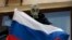 A pro-Russia rebel wearing a gas mask places a Russian flag on the balcony of the city hall in Mariupol, eastern Ukraine May 7, 2014. 