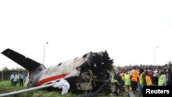 Rescue workers stand near the tail of a plane at the site of a plane crash near the Lagos airport.