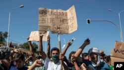 FILE: Migrants take part in a rally as the banner reads in German "Germany Please Help Us" near Mytilene town, on the northeastern island of Lesbos, Greece. 9.11.2020