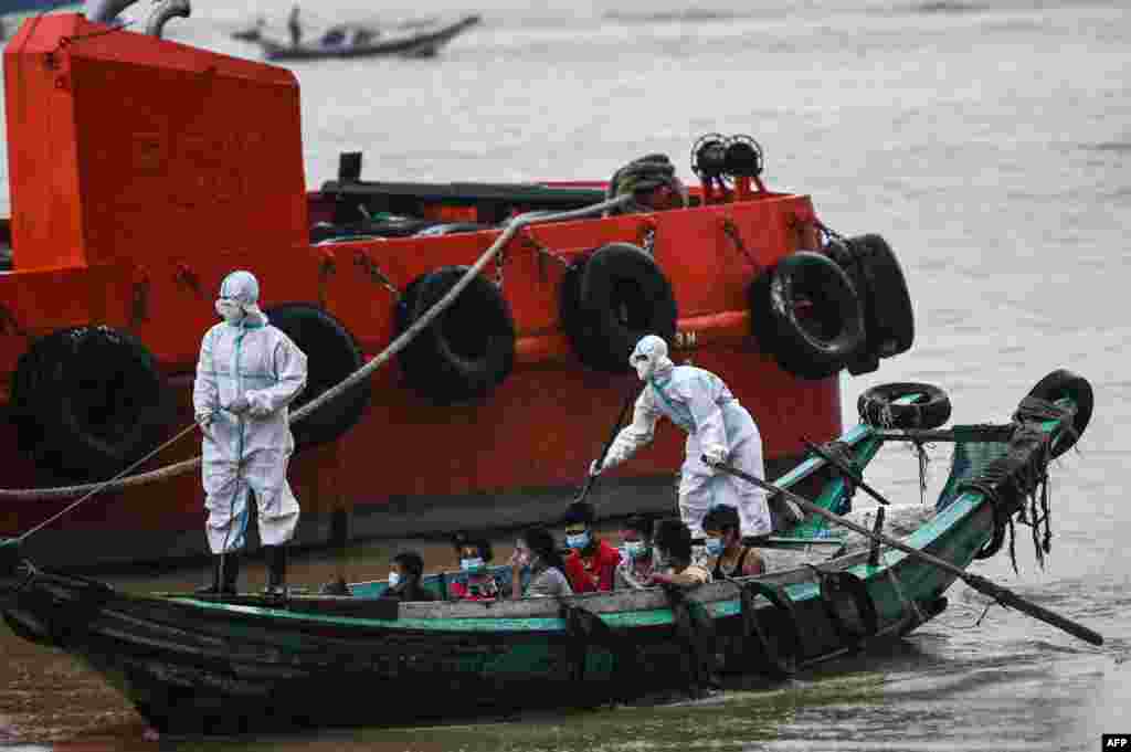 Volunteers wearing personal protective equipment (PPE) on a boat transfer people suspected of having the coronavirus to a quarantine center in Yangon, Myanmar.