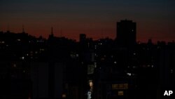 FILE - The capital city of Beirut remains in darkness during a power outage as the sun sets, in Beirut, Lebanon, March 29, 2021.