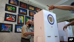 An Armenian man reads his ballot papers at a polling station during a parliamentary election in Yerevan, Armenia, June 20, 2021. 