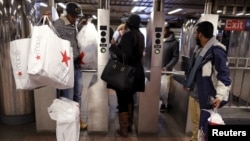 Shoppers enter the Herald Square subway station after early morning Black Friday shopping in New York, Nov. 27, 2015. 