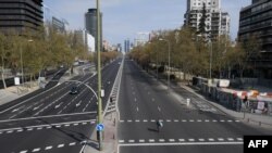 A woman crosses the usually busy La Castellana avenue in Madrid, Spain, the latest European nations to severely curtail people's movements to fight the coronavirus pandemic.