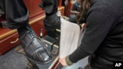 Bertha Gomez shines a customer's shoes at the Alpha Shoe Repair Corp., Friday, Feb. 3, 2023, in New York. Once a common business, the tradition of getting a quick shine like this one has become more of a rarity. (AP Photo/Mary Altaffer)