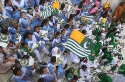 Pakistani students wave Pakistani and Kashmiri flags at the mausoleum of Muhammad Ali Jinnah, founder of Pakistan, to celebrate the Independence Day in Karachi, Pakistan, Aug. 14, 2019.