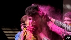 Indians put colored powder on each other as they celebrate Holi in Jammu.
