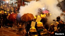 Demonstran di Hong Kong mencari perlindungan setelah polisi menembakkan gas air mata dalam aksi protes hari Minggu (21/7). 