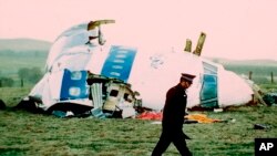 FILE - A police officer walks by the nose of Pan Am Flight 103 in a field near the town of Lockerbie, Scotland where it lay after a bomb aboard exploded, killing a total of 270 people, Dec. 21, 1988.