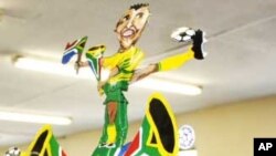 Alfred Baloyi, wearing a makarapa decorated with the image of South African football legend, Lucas Radebe, inside his factory in Johannesburg