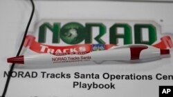 A pen rests on the playbook for volunteers who will be taking calls from around the globe in the NORAD Tracks Santa center at Petserson Air Force Base, Dec. 23, 2019, in Colorado Springs, Colo.