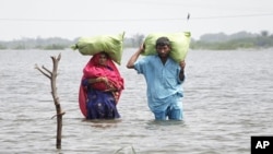 A couple carry their belongings as they wade through flood waters in the village of Ali Nawaz Khuso, Badin district of Pakistan's Sindh province, September 14, 2011.