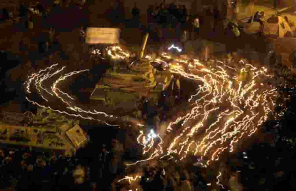 Anti-government protestors hold candles as they walk surrounding an Egyptian Army tank at Tahrir square in Cairo, Egypt, Wednesday, Feb. 9, 2011. Protesters appear to have settled in for a long standoff, turning Tahrir Square into a makeshift village with