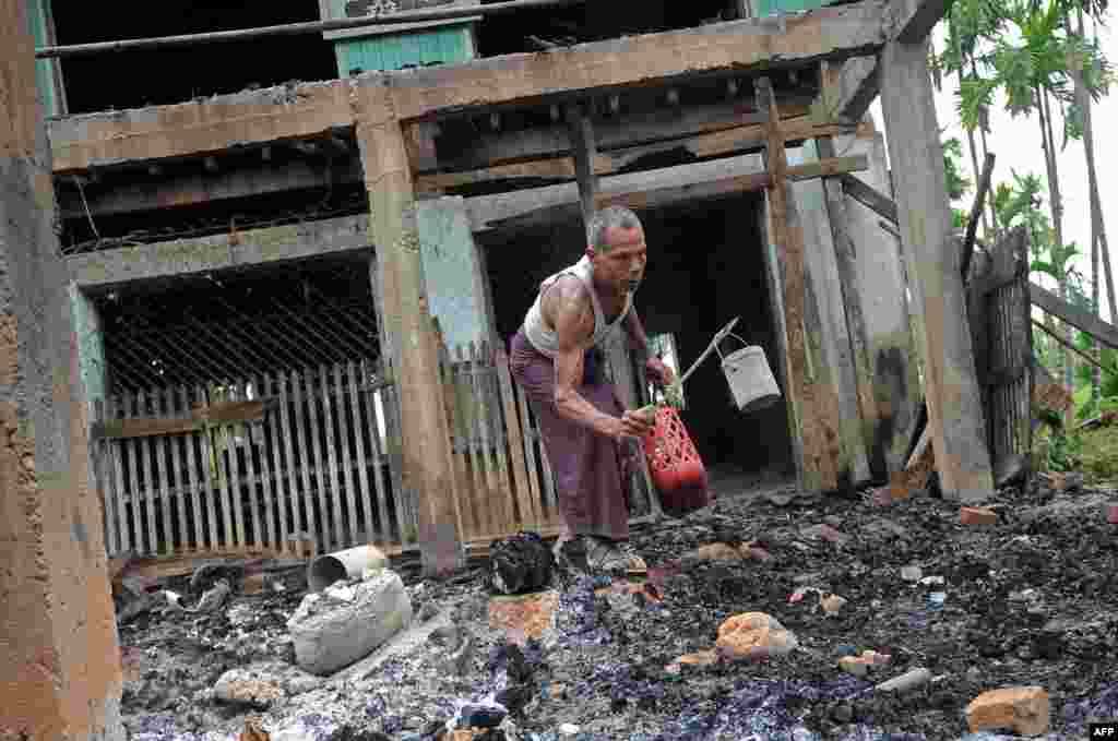 Seorang pria menyelamatkan barang-barang dari sebuah masjid yang dibakar menyusul bentrokan sektarian di desa Thabyu Chi, negara bagian Rakhine, Burma.