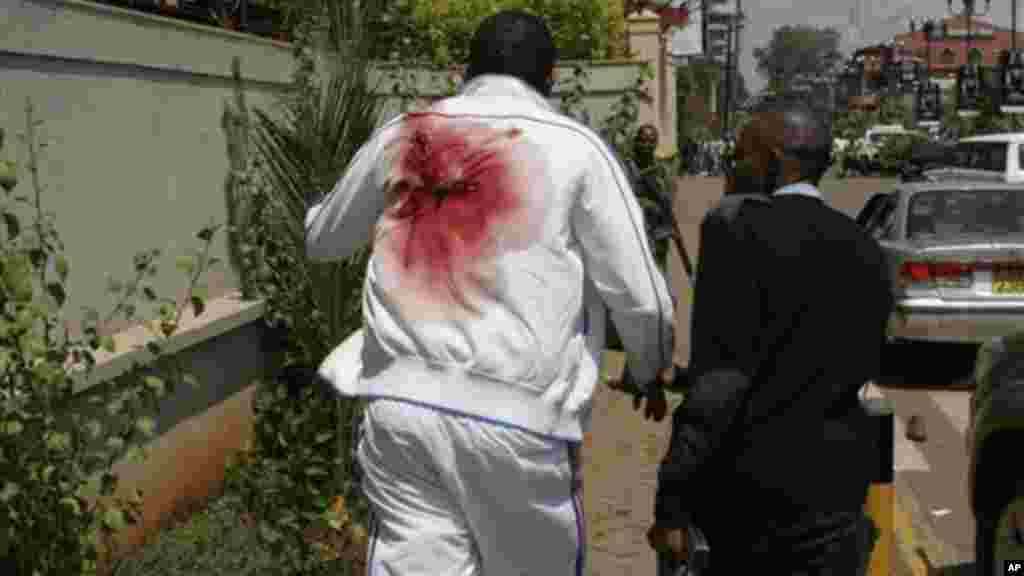 A wounded man is escorted outside the Westgate Shopping Mall, an upscale shopping mall in Nairobi, Kenya Saturday Sept. 21 2013.