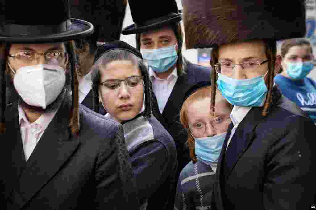 Members of Jewish Orthodox community gather around a journalist as he conducts an interview on a street corner, Oct. 7, 2020, in the Borough Park neighborhood of the Brooklyn borough of New York.