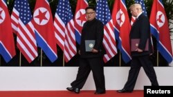 U.S. President Donald Trump and North Korea's leader Kim Jong Un walk during their summit at the Capella Hotel on Sentosa island in Singapore, June 12, 2018.