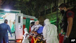Health workers evacuate a woman from a nursing home after residents of the facility tested positive for the new coronavirus, in Buenos Aires, Argentina, May 7, 2020. 