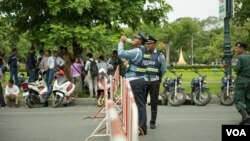 FILE - A traffic police officer takes a drink of water while being dispatched to guard outside the Supreme Court building in Phnom Penh, Cambodia, on August 22, 2018. (Ty Aulissa/VOA Khmer)