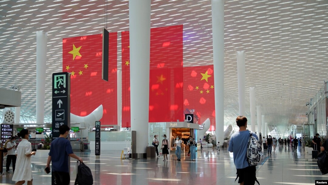 Pelancong berjalan melewati bendera Tiongkok jelang libur Hari Nasional dan Pekan Emas Tiongkok, di Bandara Internasional Baoan Shenzhen di Shenzhen, Provinsi Guangdong, Tiongkok 30 September 2021. (Foto: REUTERS/Aly Song)