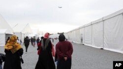 Afghan refugees walk alongside temporary housing in Liberty Village on Joint Base McGuire-Dix- Lakehurst in Trenton, N.J., Dec. 2, 2021.