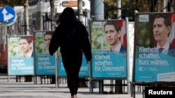 A person passes election campaign posters of the head of Austria's Peoples Party (OeVP) and former Chancellor Sebastian Kurz in Vienna, Austria, Sept. 23, 2019. 