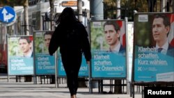 A person passes election campaign posters of the head of Austria's Peoples Party (OeVP) and former Chancellor Sebastian Kurz in Vienna, Austria, Sept. 23, 2019. 