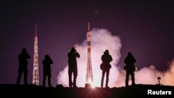 Photographers take pictures as the Soyuz MS-12 spacecraft carrying Aleksey Ovchinin of Russia, Nick Hague and Christina Koch of the U.S. blasts off to the International Space Station (ISS) from the launchpad at the Baikonur Cosmodrome, Kazakhstan, March 15, 2019.