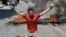 A protester carries stones in one hand and a beer bottle in the other as he kneels in front of burning tires set by protesters in front of Luxor governorate building to protest against the newly-appointed governor, Adel Mohamed al-Khayat, who was a member