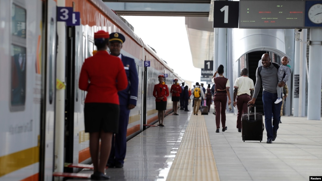 FILE - A man carries an infant as he walks along the platform in front an SGR train traveling to Mombasa from the Nairobi SGR Terminus, outside Nairobi, Kenya, October 22, 2019. 