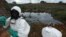 Waste removal experts work to extract hazardous black sludge from a garbage dump in Abidjan, Ivory Coast, September 17, 2006. (AP)