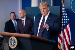 President Donald Trump speaks, accompanied by Food and Drug Administration Commissioner Dr. Stephen Hahn, center, during a media briefing in the James Brady Briefing Room of the White House, Aug. 23, 2020, in Washington.