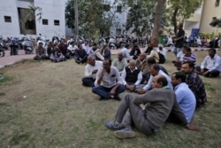 FILE - Relatives of victims of Saturday's fire at the Nandan Denim garment factory, one of the largest denim suppliers in the world, wait to receive bodies outside a hospital in Ahmedabad, India, Feb. 11, 2020.