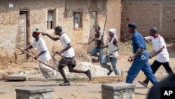 FILE - Members of the Imbonerakure pro-government youth militia chase after opposition protesters, unhindered by police, in the Kinama district of the capital Bujumbura, in Burundi, May 25, 2015. 