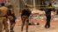 Des éléments forces de sécurité burkinabè se tiennent près du corps d'un suspect jihadiste abattu à Ouagadougou, le 22 mai 2018.