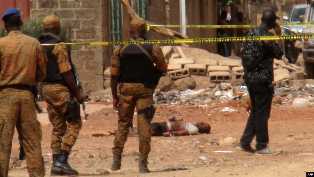 FILE - Burkina Faso security force personnel stand next to the body of a suspected jihadist in Ouagadougou, May 22, 2018, after a pre-dawn raid by security forces on a house in the capital of Burkina Faso.