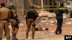 FILE - Burkina Faso security force personnel stand next to the body of a suspected jihadist in Ouagadougou, May 22, 2018, after a pre-dawn raid by security forces on a house in the capital of Burkina Faso.