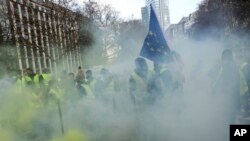 Demonstrators, called the yellow jackets, holds up an EU flag during a protest against rising fuel prices in Brussels, Friday, Nov. 30, 2018.