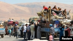 Syrian refugees, fleeing the recent fighting in Arsal, wait by trucks in the Bekaa valley, near the Lebanese border with Syria.