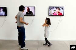 People listen to video portraits by family members of the 43 college students who went missing in an apparent 2014 massacre at an art exhibit titled "Reestablish Memories" by Chinese concept artist and government critic Ai Weiwei at the Contemporary Art University Museum in Mexico City, April 13, 2019.