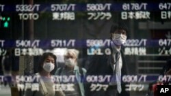 FILE - People are reflected on a blank electronic stock board supposedly showing Japan's Nikkei 225 index at a securities firm.