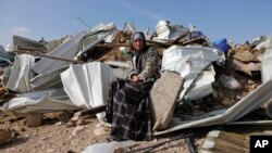 A Bedouin woman sit on demolished structure of a house in the Bedouin village of Umm al-Hiran, near the southern city of Beersheba, Israel Wednesday, Jan. 18, 2017.